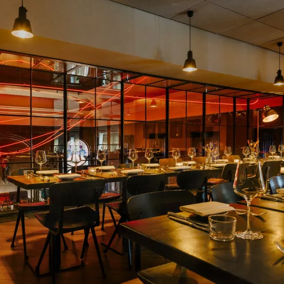 Modernes Restaurant mit gedeckten Tischen und warmem, stimmungsvollem Licht.