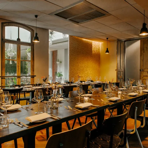 Lang gedeckter Tisch in stilvollem, warm beleuchtetem Restaurant.