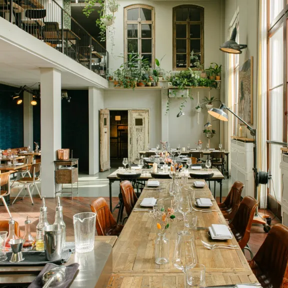 Helles, modern eingerichtetes Restaurant mit langen Holztischen und Pflanzen.