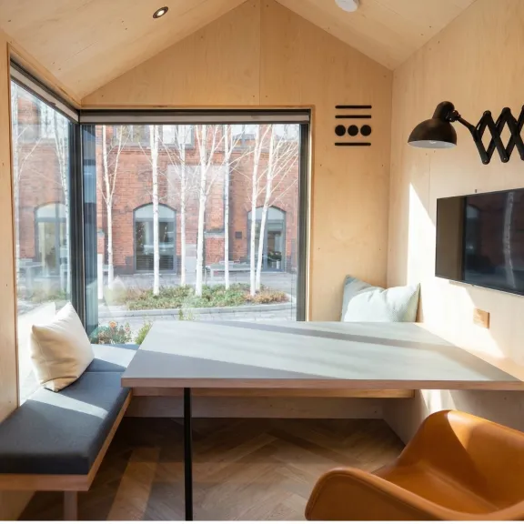 Helles, modernes Besprechungszimmer mit großem Fenster, Tisch und Sitzbank.