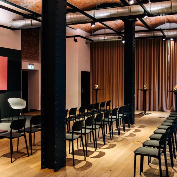 Konferenz mit Reihenbestuhlung, Bühne und Loungeecke unter historischen Kappendecken im Firespace Berlin-Mitte