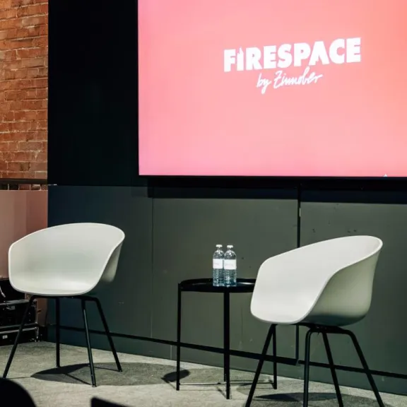 Panel-Bühne mit zwei Sesseln und 100-Zoll-LED-Display für Talks und Produktpräsentationen im Firespace