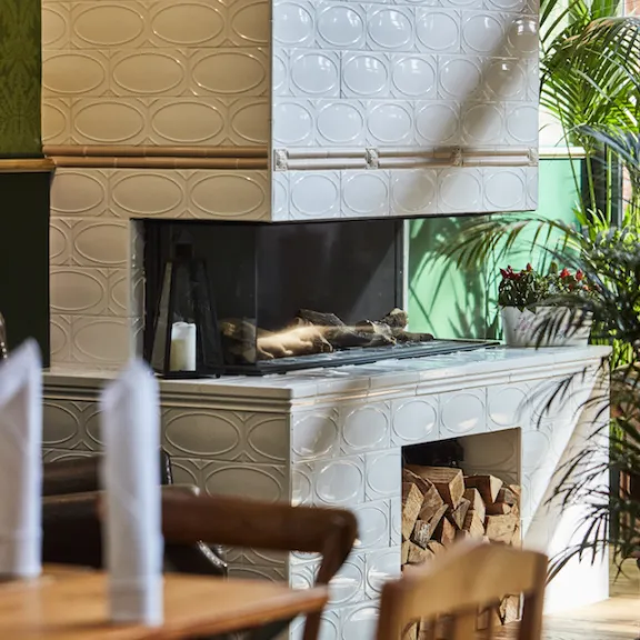 Gemütlicher Gastraum mit modernem Kamin, Holztisch und grünen Pflanzen