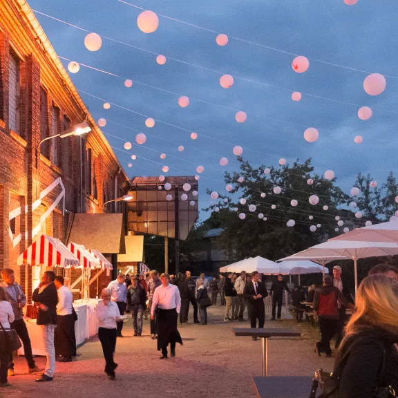 Abendliches Event mit Lichterketten, Menschen und Marktständen.