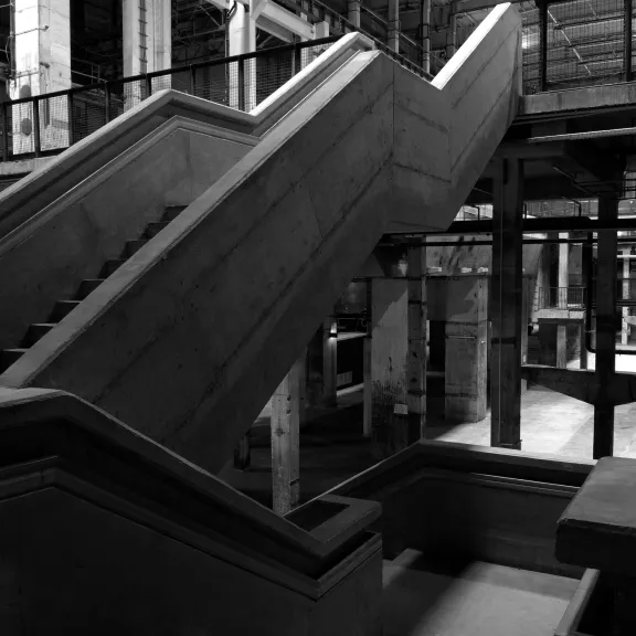 Schwarz-weiß Foto einer breiten Treppe in einer Industriehalle