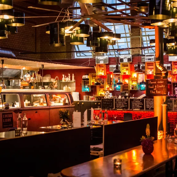 Gemütliches Restaurant mit bunter Beleuchtung und modernen Möbeln, warme Atmosphäre.