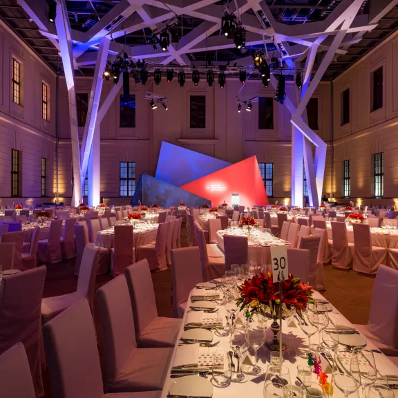 Großer, festlich beleuchteter Saal mit elegant gedeckten Tischen und moderner Dekoration.