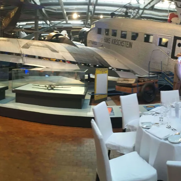 Tische in Bankettbestuhlung im Technikmuseum mit einem alten Austellungsflugzeug im Hintergrund