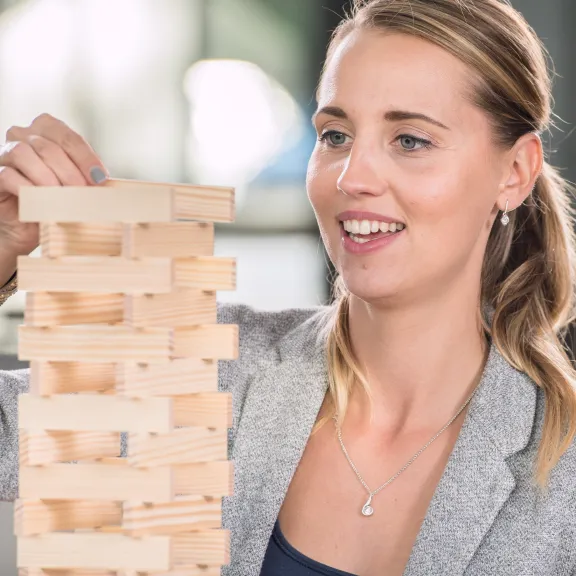 Meeting Guide Berlin Teamgeist Frau baut mit Kapla Steinen einen Turm