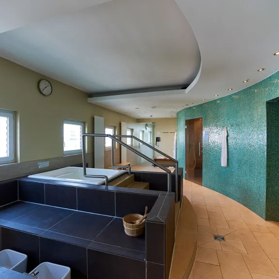 Modernes Spa mit Whirlpools, grünen Wandfliesen und Handtuchhaltern.
