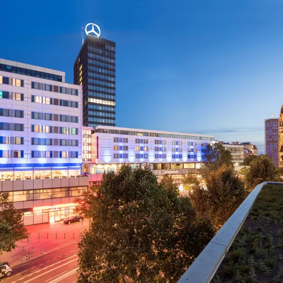 Moderne Stadtansicht bei Dämmerung mit beleuchteten Gebäuden und Hochhäusern.