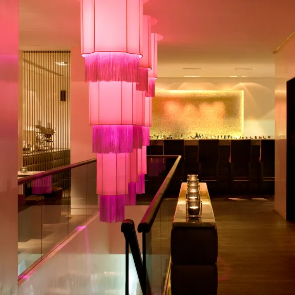 Modernes Restaurant mit pink beleuchteten Lampen und stilvollem, gemütlichem Ambiente.