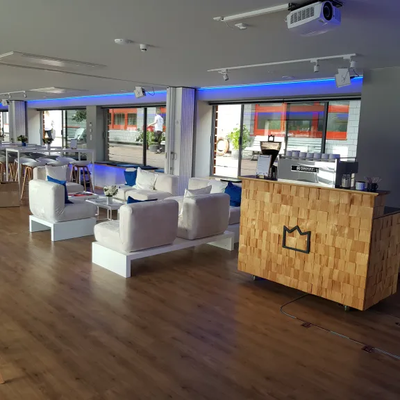 Modernes Café mit weißen Möbeln, Holzfußboden und blauem Licht an den Fenstern.