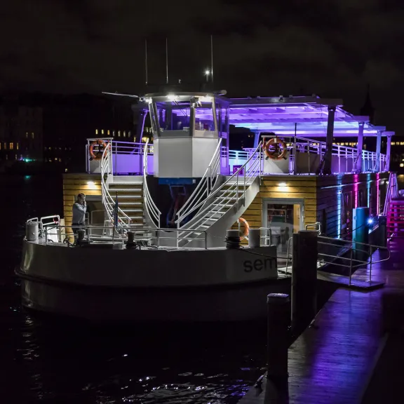 Beleuchtetes Ausflugsschiff am Abend am dunklen Steg.