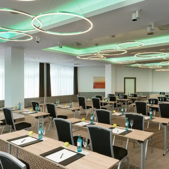 Heller Konferenzraum mit modernen Deckenleuchten, Reihen von Tischen und Stühlen