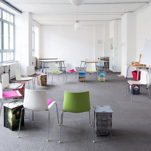 Raum mit grauem Teppich und bunten Stühlen