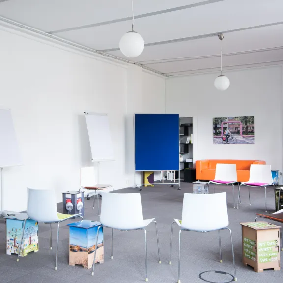 raum mit grauem Teppich, orangenem Sofa, blauer Pinnwand