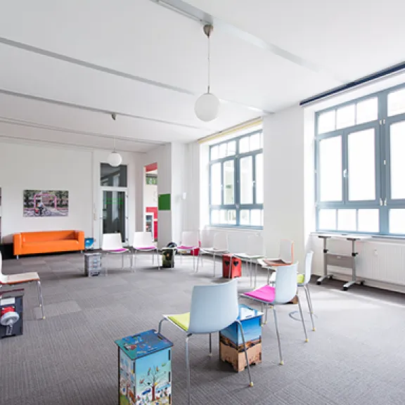 Raum mit grauem Teppich und bunten Stühlen