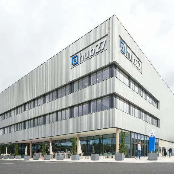 Modernes Bürogebäude mit TRUMPF-Logo und Glasfassade an einem bewölkten Tag.