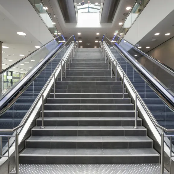 Breite Treppe zwischen zwei Rolltreppen in einem modernen Gebäude