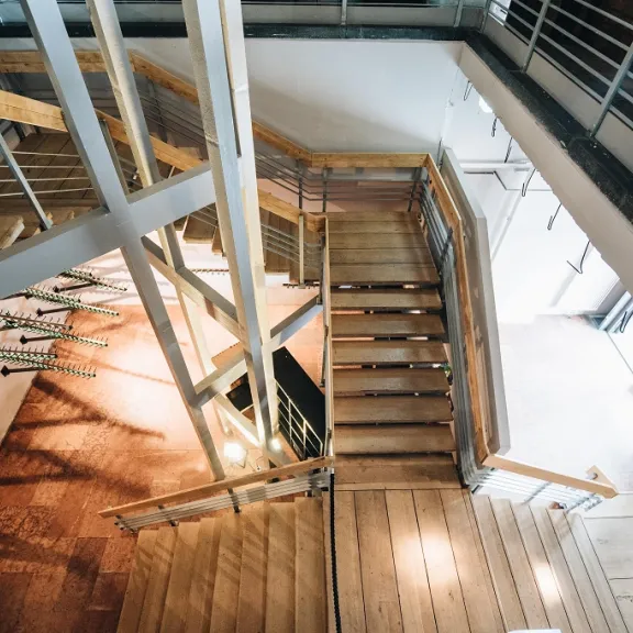 Holztreppe in einem modernen Gebäude mit Metallgeländern aus der Vogelperspektive.