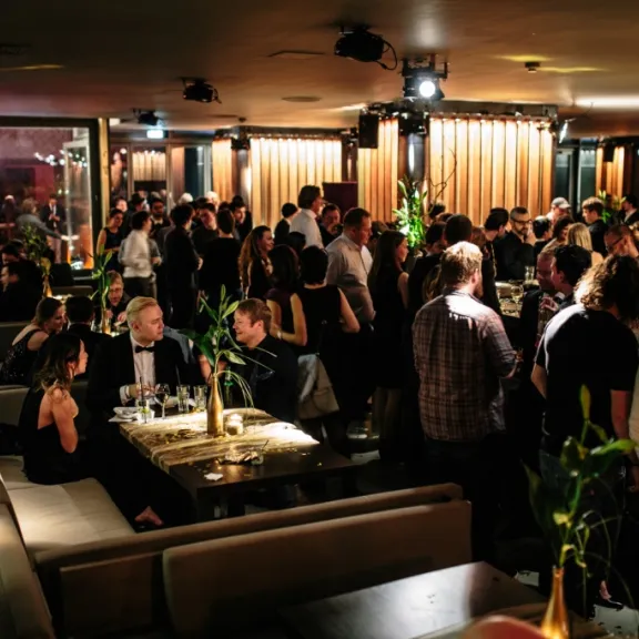 Viele Menschen in eleganter Kleidung feiern abends in einem stilvollen Restaurant.