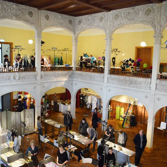 Menschen und Ausstellungstische bei einer Ausstellung im Saal der Villa Elisabeht