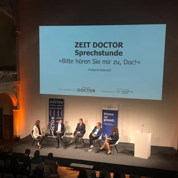 Blick auf eine Bühne mit Menschen und Projektion auf Leinwand im Saal der Villa Elisabeth