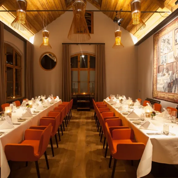 Elegantes Restaurant mit langen, festlich gedeckten Tischen und warmem Licht.