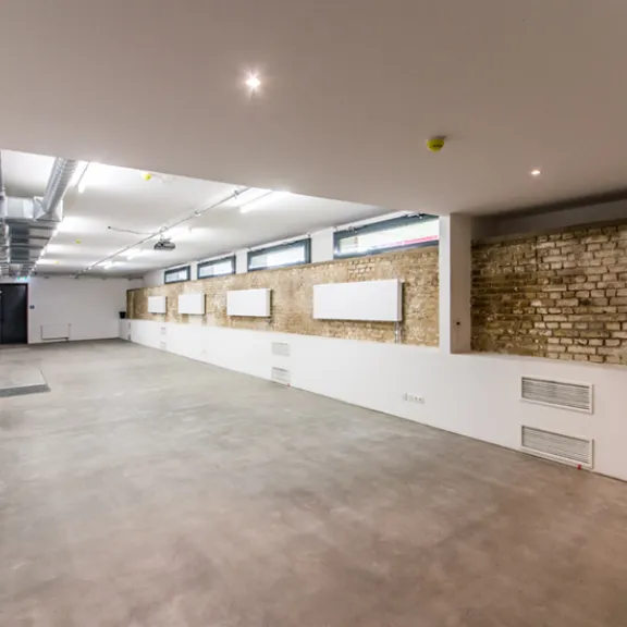 Rustikale Backsteinwände, ein Betonboden, seine schlauchartige Form sowie eine schmale Fensterfront geben dem Lichtkeller im Souterrain des Kachelhauses einen klaren Look. 