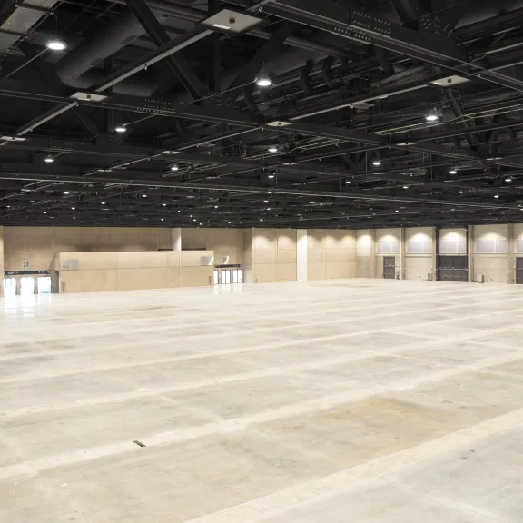 Große leere Messehalle mit Betonboden und heller Beleuchtung