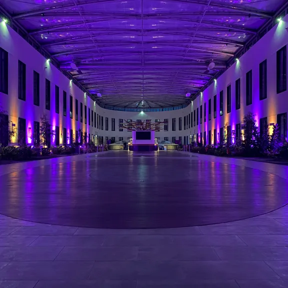 Große Halle mit lila Beleuchtung und dekorativen Lichtern entlang der Wände.