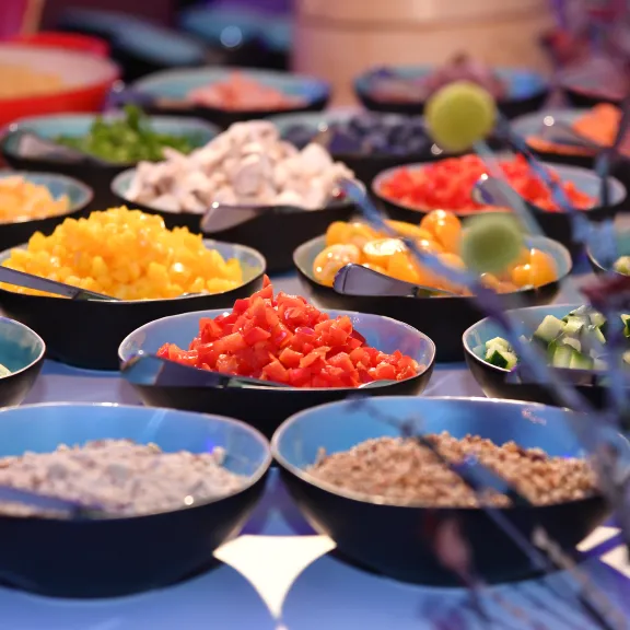 Verschiedene bunte Zutaten in Schalen auf einem Tisch, nah aufgenommen.