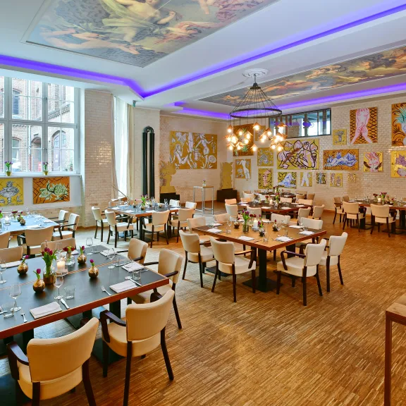 Helles Restaurant mit modernen Tischen, Stühlen und vielen Kunstwerken an den Wänden.