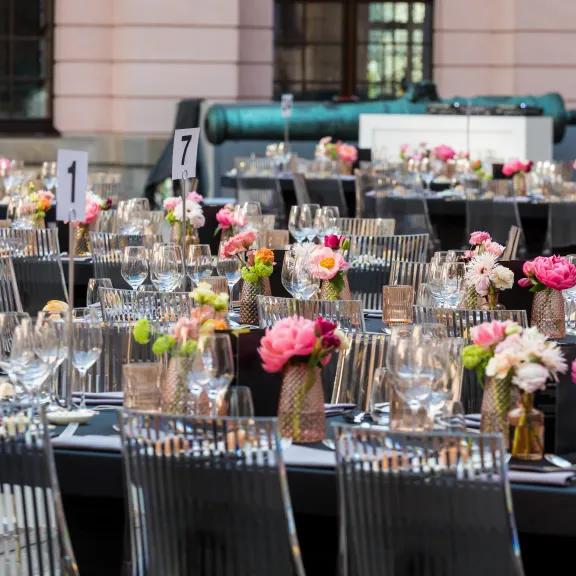 Festlich gedeckte Tische mit Blumen und Gläsern im Freien.