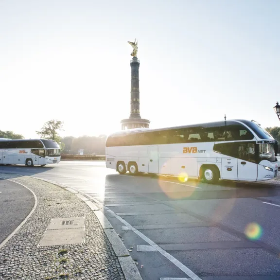 Zwei Busse von Bus Verkehr Berlin fahren durch Berlin, im Hintergrund die Siegessäule.