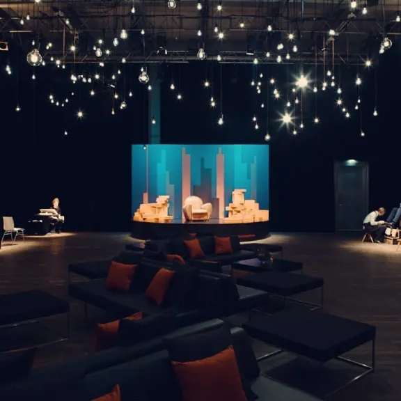 Moderne Lounge mit Sofas, stimmungsvoller Beleuchtung und Bühne im Hintergrund