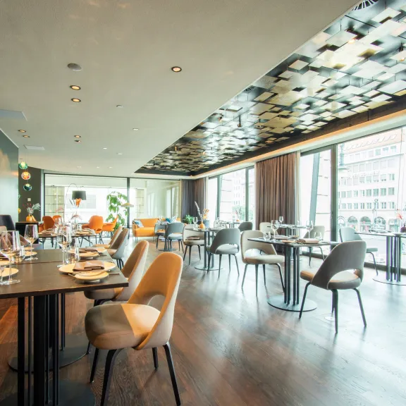 Modernes Restaurant mit großen Fenstern, eleganter Einrichtung und Holzboden.