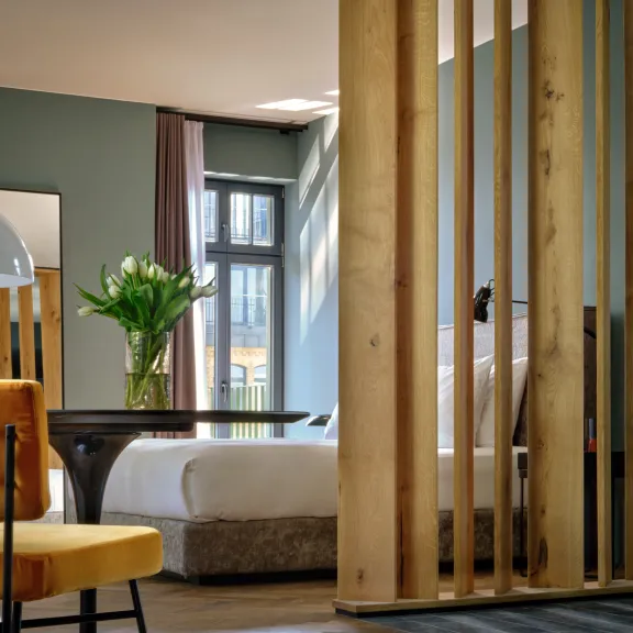 Modernes Schlafzimmer mit gelbem Sessel, Holzwand und großem Fenster