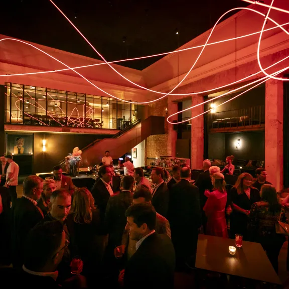 Menschen in eleganter Abendkleidung feiern in stimmungsvoll beleuchtetem Raum.