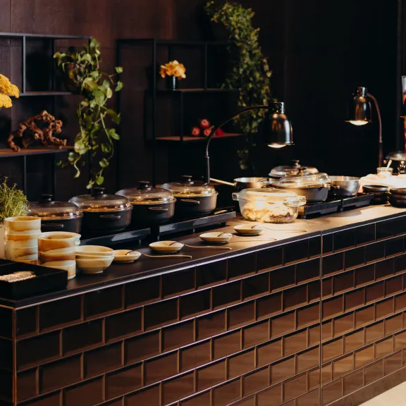 Buffet mit verschiedenen Speisen, dekoriert mit Blumen und Grünpflanzen.