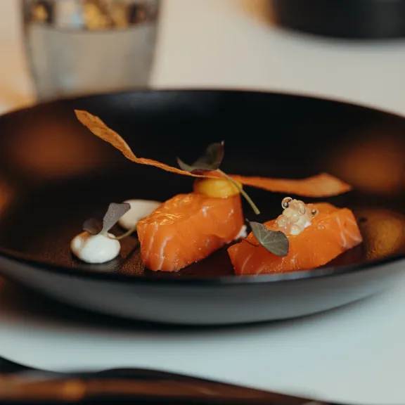 Lachsfilets mit Deko auf schwarzem Teller, moderne Anrichtung