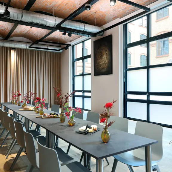 Langer Konferenztisch mit dekorativen Blumenvasen in modernem, hellem Raum