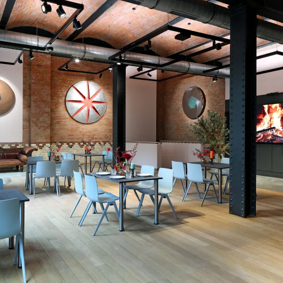 Modernes Café mit Holzboden, Tischen, Stühlen, Wanddeko und Kamin auf Bildschirm.