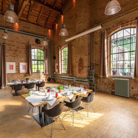 Ein großer, heller Raum mit Backsteinwänden und gedecktem Tisch für eine Gruppe.