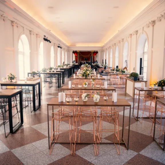 Eleganter, heller Saal mit festlich gedeckten Tischen und Blumenarrangements.
