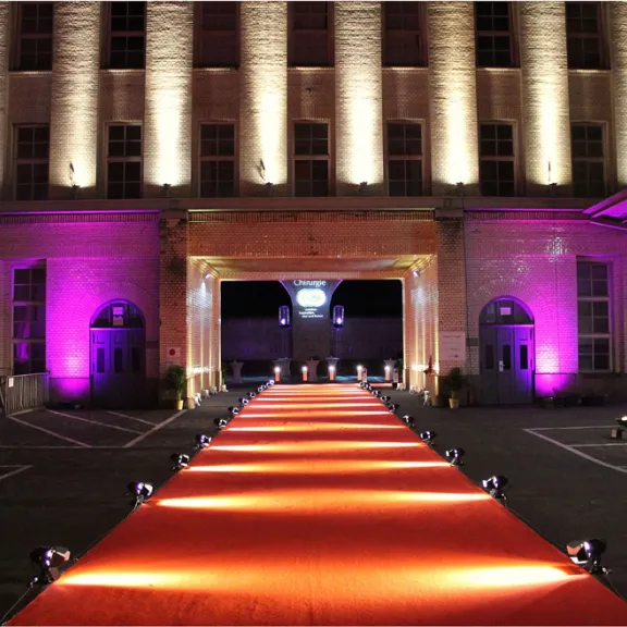 Roter Teppich mit Scheinwerfern vor einem beleuchteten Gebäude bei Nacht