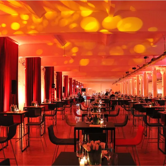 Modernes Restaurant mit stimmungsvoller roter Beleuchtung und festlich gedeckten Tischen.