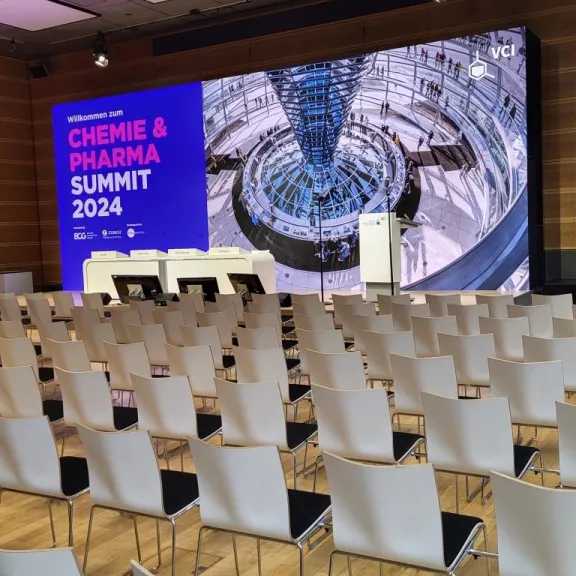 Leerer Vortragssaal mit Bühne, Rednerpult und großem Bildschirm für Chemie & Pharma Summit 2024.