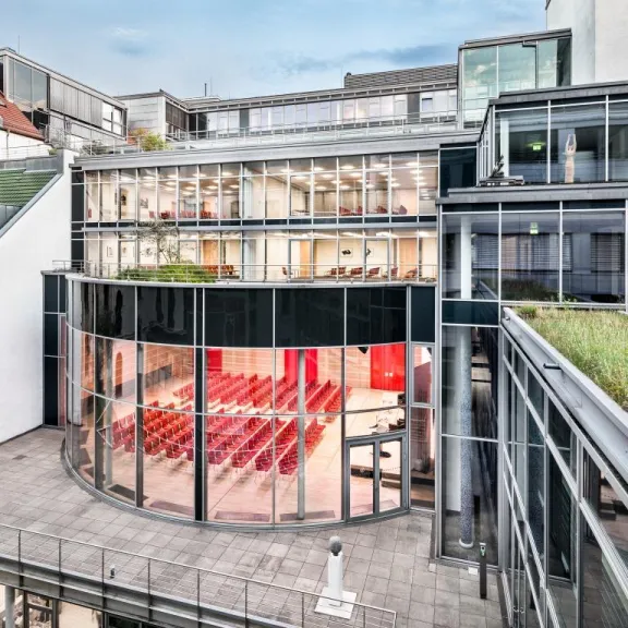 Modernes Gebäude mit Glasfassade und rotem Bestuhlungsraum im Innenhof